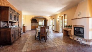A spacious kitchen with a dining area, featuring a fireplace, a kitchen island, and an arched doorway leading to another room.