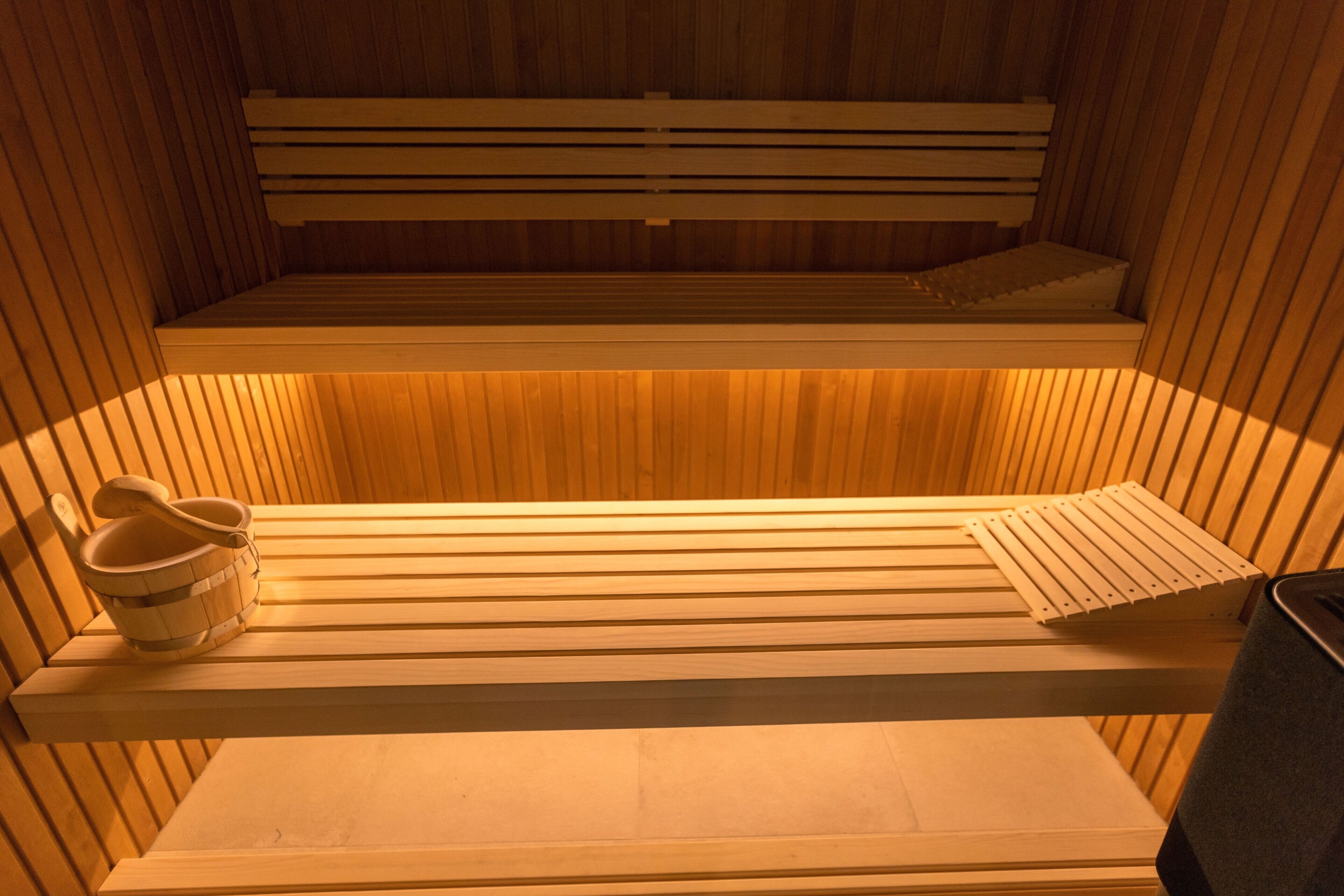 A sauna with wooden benches and a bench with a towel rack.