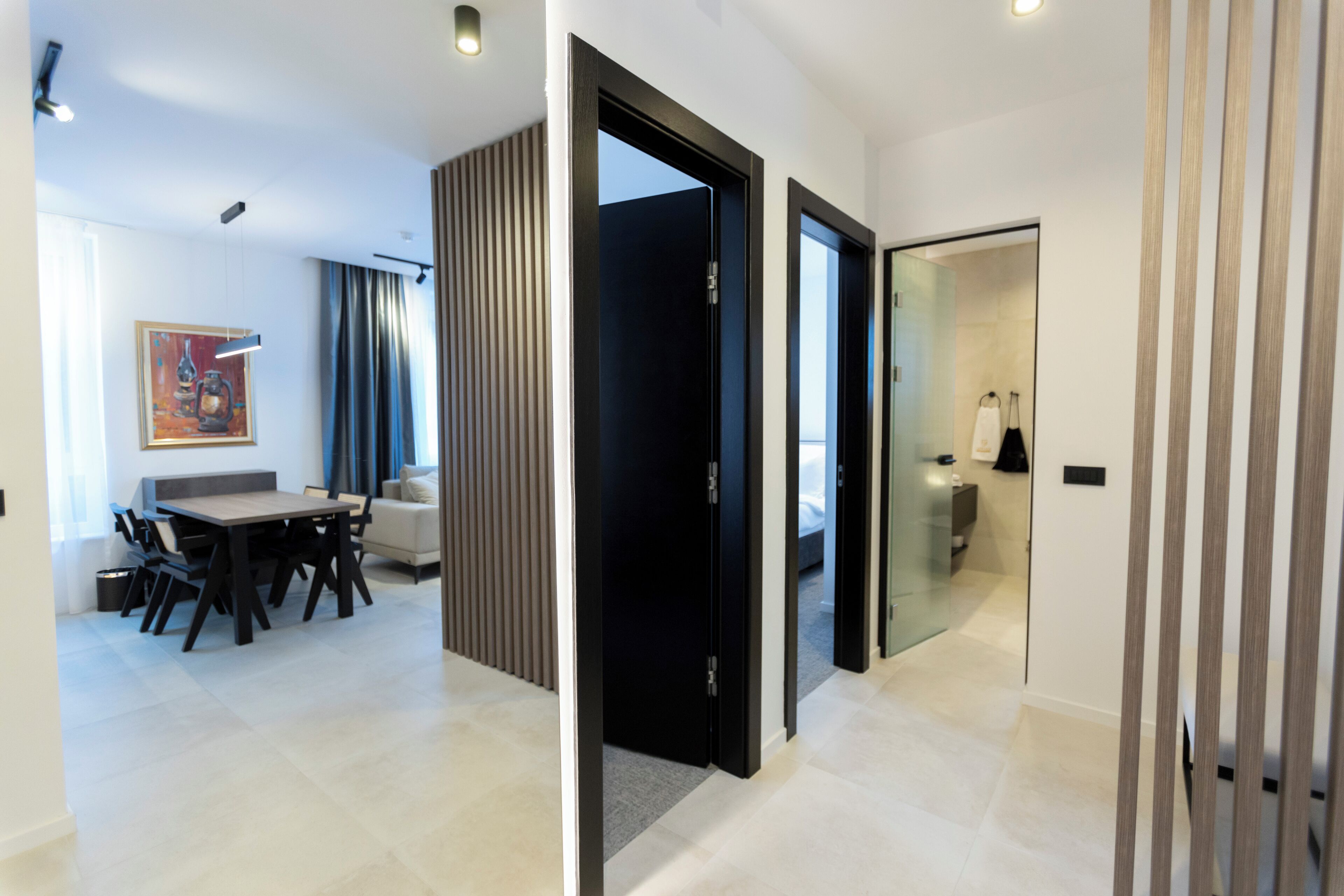 A modern hotel room with a dining area, a sofa, and a glass partition.