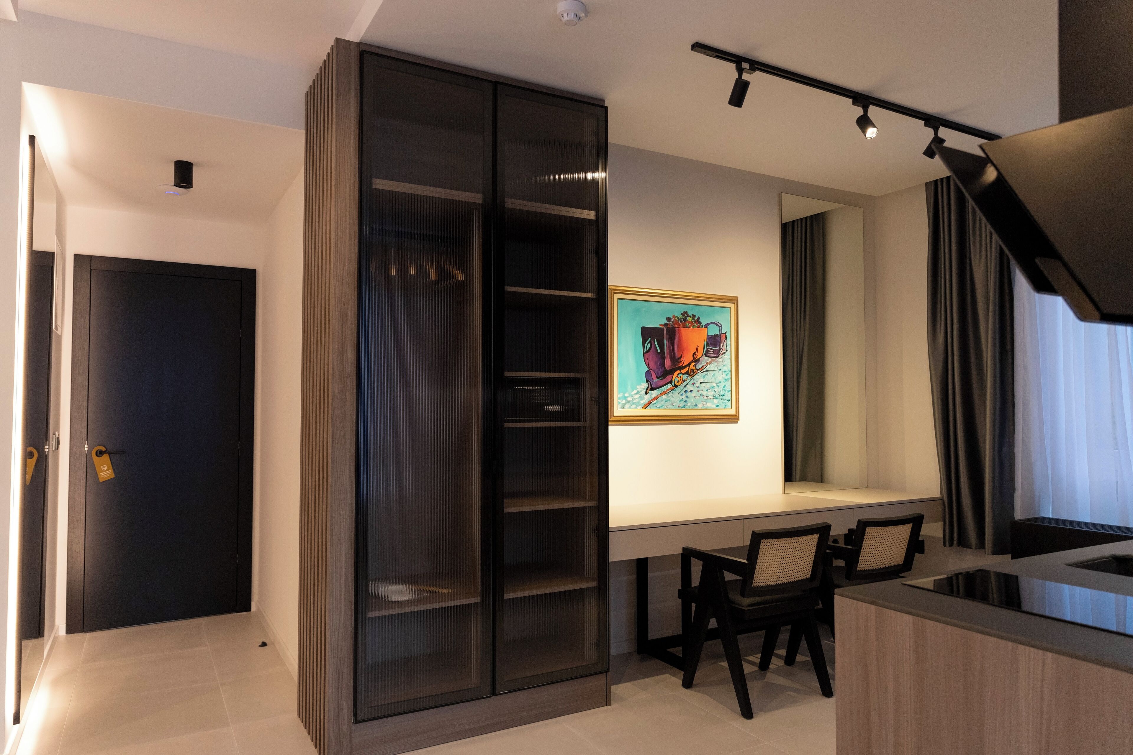 A modern kitchen with a dining area, a sliding glass door closet, and a painting on the wall.
