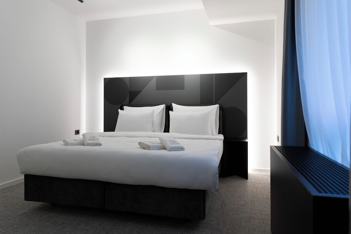 A modern hotel room with a large bed, a headboard, and a bedside table.