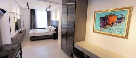Quarto de hotel moderno com cama, mesa de cabeceira e uma grande pintura na parede.