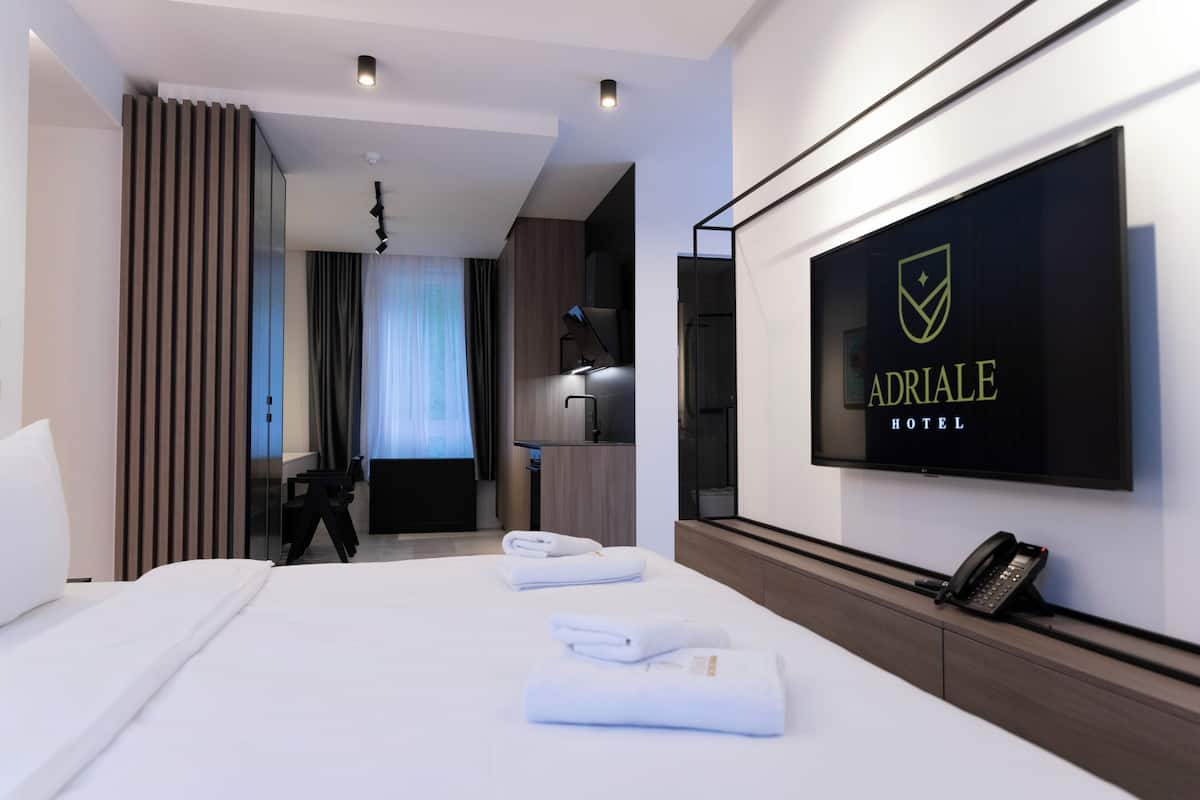 A hotel room with a bed, a TV mounted on the wall, and a desk with a telephone.