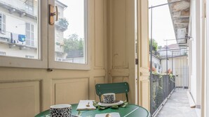 A narrow outdoor corridor with a green chair and a table with a cup and saucer. - Lagrange Design Apartment by Wonderful Italy - Alfa (Turin)