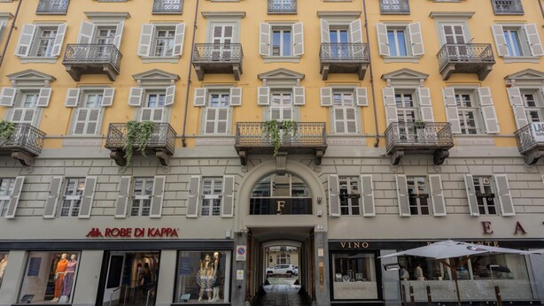 A building with multiple balconies, storefronts including 'ROBE DI KAPPA' and 'VINO', and a central archway labeled 'F'. - Lagrange Design Apartment by Wonderful Italy - Alfa (Turin)