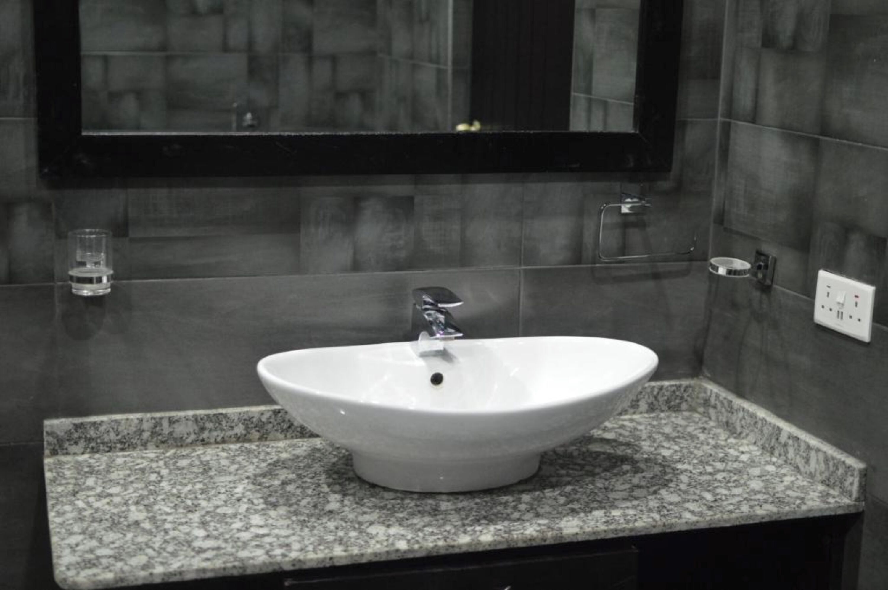 A bathroom with a white sink, granite countertop, and a mirror above it.
