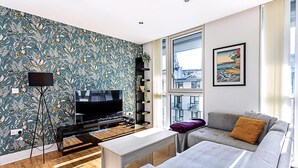 A modern living room with a large TV, a sofa, and a coffee table. - City-Close 1-Bed Apartment near Tower Hill (London)
