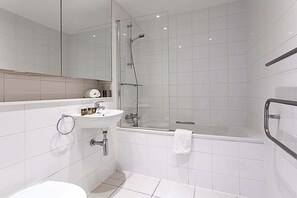 A modern bathroom with a glass-enclosed shower, a white sink, and a bathtub. - City-Close 1-Bed Apartment near Tower Hill (London)