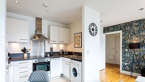 A modern kitchen with white cabinetry, stainless steel appliances, and a central island. - City-Close 1-Bed Apartment near Tower Hill (London)