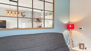 Un salón moderno con un espejo grande, un sofá gris, una lámpara de pie roja y una mesita con un farol.
