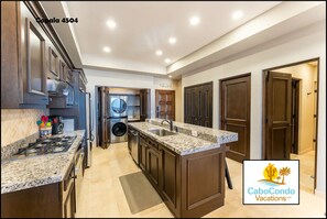 A modern kitchen with granite countertops, stainless steel appliances, and dark wood cabinetry. - CCV Quivira - Luxurious 2BR w/ Ocean Views and Golf access! (Cabo San Lucas)