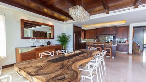 A modern kitchen with wooden cabinets, a large island with chairs, and a hanging light fixture. - Calm and Cosy 4 Bedroom Condo (Punta de Mita)