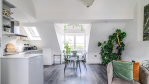 A modern kitchen with a dining area, featuring a skylight, a large plant, and a cozy seating area. - Gorgeous Hampstead Flat (London)