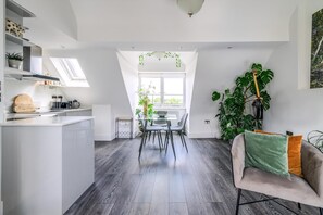 A modern kitchen with a dining area, featuring a skylight, a large plant, and a cozy seating area. - Gorgeous Hampstead Flat (London)