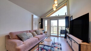 A living room with a pink sofa, a television, and a large window. - RentPlanet - Osada Górska (Szklarska Poreba)