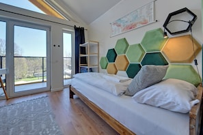 A bedroom with a bed, a view through a sliding door, a hexagonal wall decoration, and a map on the wall. - RentPlanet - Osada Górska (Szklarska Poreba)