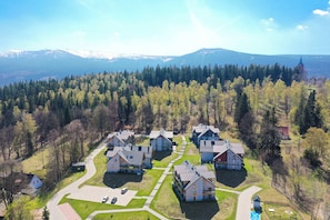 A residential area with houses, a road, and a forested mountain range in the background. - RentPlanet - Osada Górska (Szklarska Poreba)