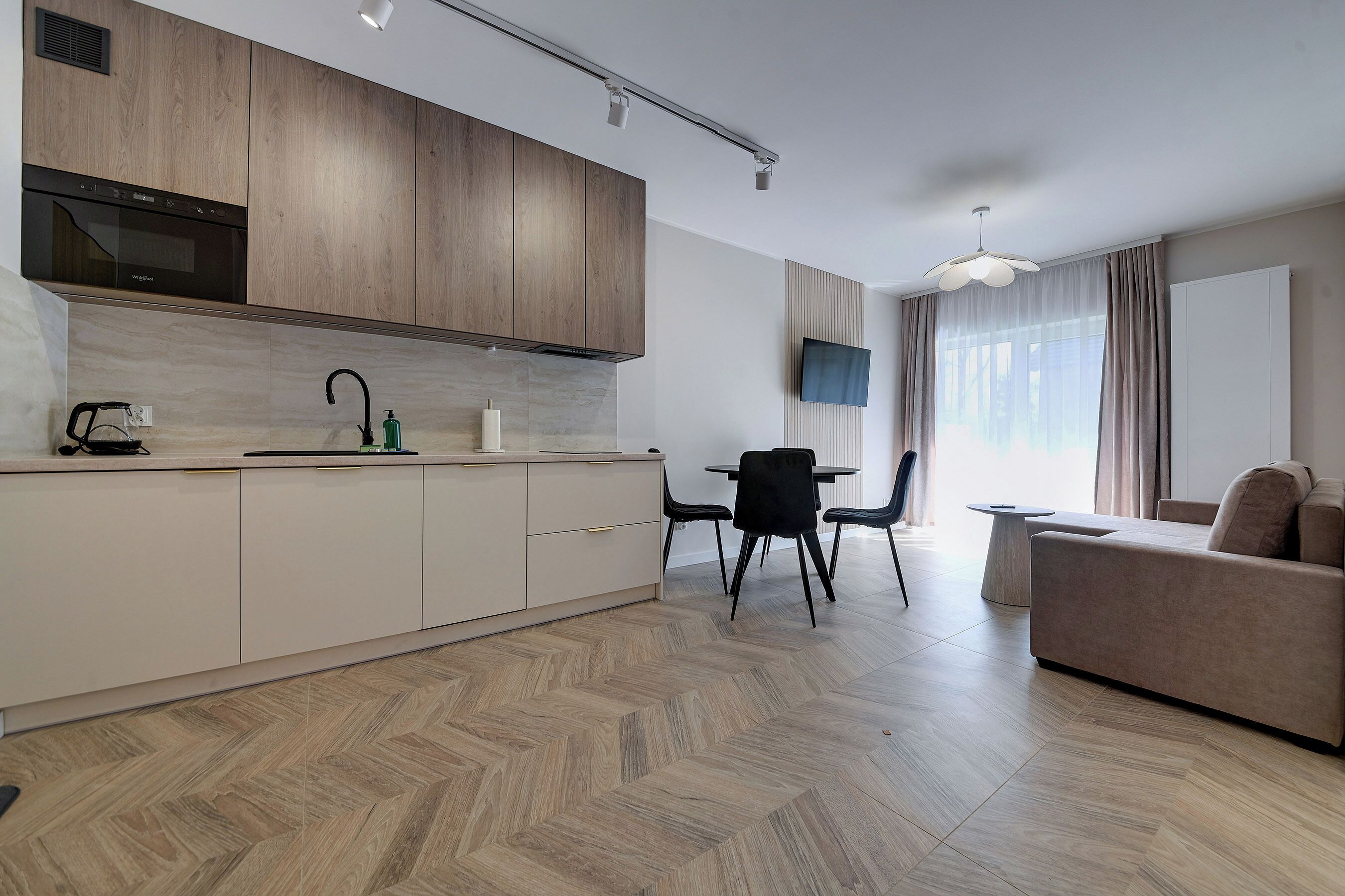 Una cocina moderna con armarios de madera, horno integrado y un comedor con mesa y sillas.