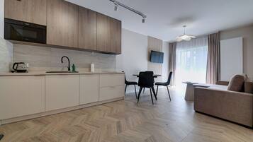 Una cocina moderna con armarios de madera, horno integrado y un comedor con mesa y sillas.