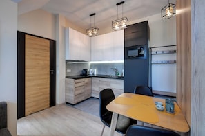 A modern kitchen with wooden cabinets, a built-in microwave, and pendant lighting. - RentPlanet - Osada Górska (Szklarska Poreba)