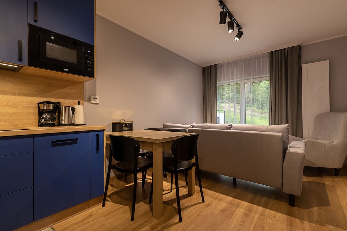 A compact living space with a kitchenette, a dining area, and a seating area with a sofa and armchairs.