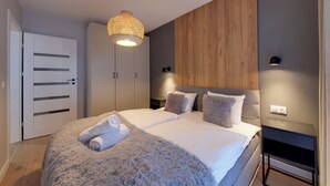A modern bedroom with a large bed, a wooden accent wall, and a hanging light fixture. - RentPlanet - Osada Górska (Szklarska Poreba)