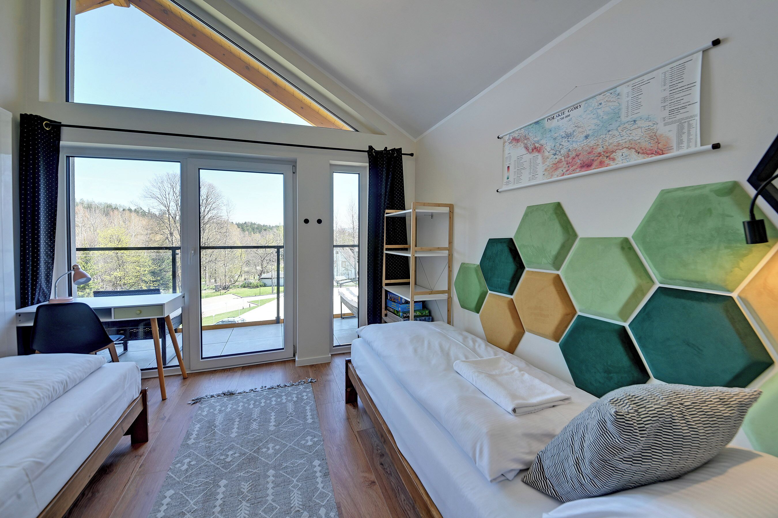 Quarto com cama, escrivaninha e vista através de uma porta de vidro.