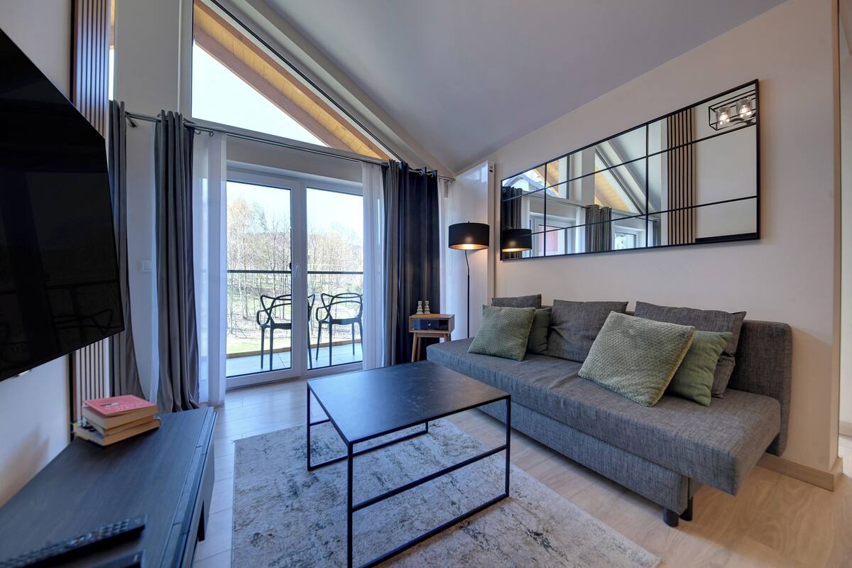 A modern living room with a sofa, coffee table, and a TV on a stand.