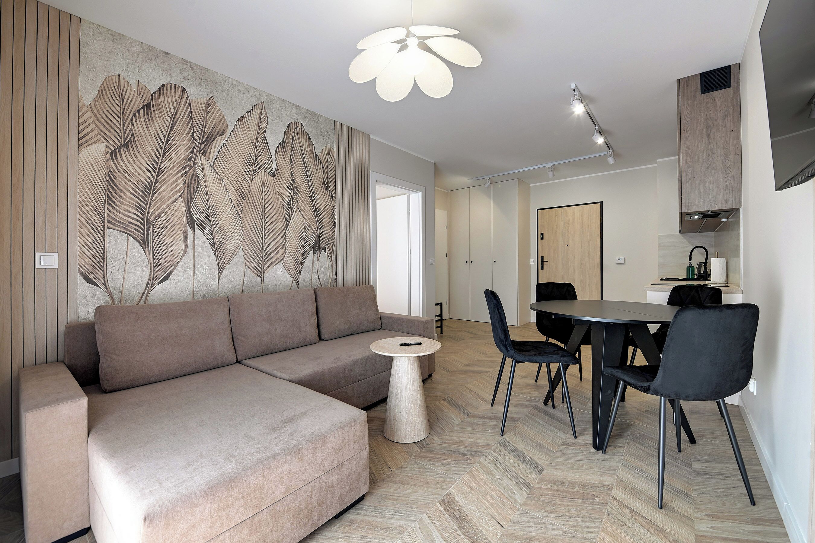 Una sala de estar moderna con un sofá seccional, una mesa de centro redonda y un comedor con mesa y sillas.