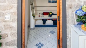 A narrow doorway leading into a room with a tiled floor, a small table with a chair, and a cabinet.