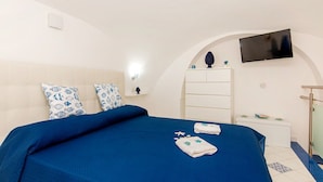 A hotel room with a bed, a TV, a bedside table, and a wardrobe.