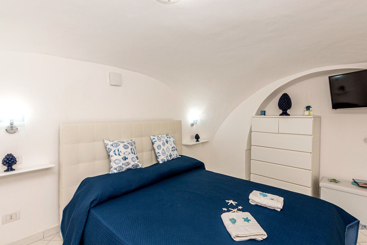 A bedroom with a bed, a TV, and a white wardrobe.