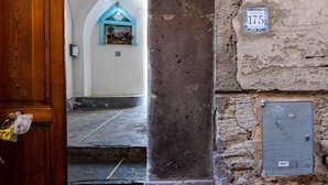 A stone building with a wooden door and a number plaque '113'.
