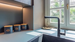 A modern kitchen with a built-in stove, a window with a view of greenery, and three containers with labels. - Lagrange Design Apartments - Beta by Wonderful Italy (Turin)