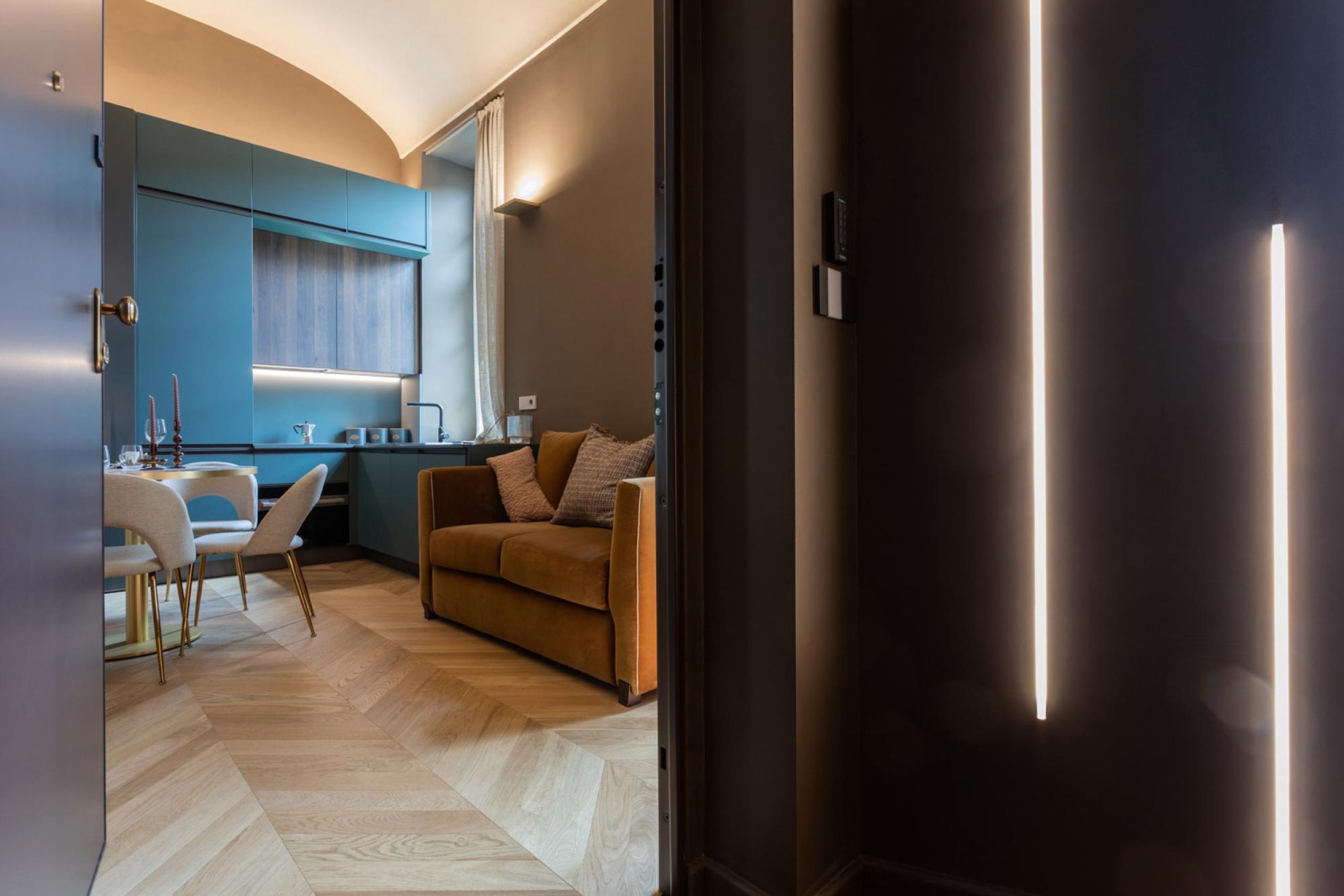 Ein modernes Wohnzimmer mit einer Couch, einem Essbereich mit Tisch und Stühlen sowie einer Küche mit Fenster und Arbeitsfläche.