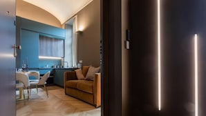 A modern living room with a sofa, a dining area with a table and chairs, and a kitchen area with a window and counter. - Lagrange Design Apartments - Beta by Wonderful Italy (Turin)