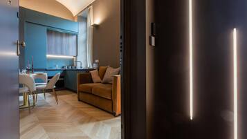 Ein modernes Wohnzimmer mit einer Couch, einem Essbereich mit Tisch und Stühlen sowie einer Küche mit Fenster und Arbeitsfläche.
