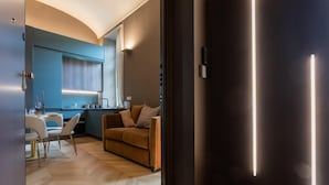 A modern kitchen with a blue cabinet, a dining area with a white table and chairs, and a sofa. - Lagrange Design Apartments - Beta by Wonderful Italy (Turin)