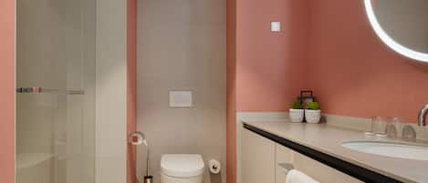 A modern bathroom with a glass shower enclosure, a toilet, and a sink with a mirror.