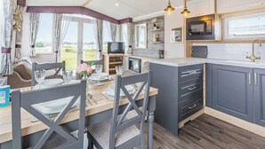 A modern kitchen with grey cabinets, a wooden dining table, and a television. - 2 bedroom accommodation in Dornoch (Dornoch)