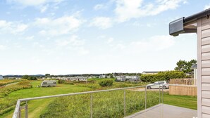 A deck with a view of a grassy field and mobile homes in the distance. - 2 bedroom accommodation in Dornoch (Dornoch)