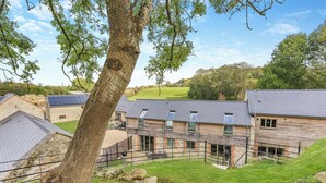 A stone building with a sloped roof, multiple windows, and a fenced courtyard. - Property 3 - UK44923 (Ventnor)