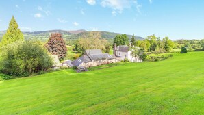 A rural landscape with a stone house, a large lawn, and a hill in the background. - The Chapel - UK45026 (Crickhowell)