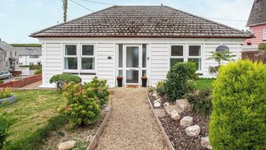 A single-story house with a tiled roof, a front door, and a small garden with gravel paths and various plants. - 2 bedroom accommodation in Foxhole, near St. Austell (Foxhole, near St. Austell)