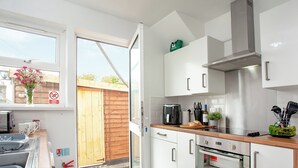 A modern kitchen with white cabinets, a stainless steel range hood, a coffee maker, and a fire extinguisher. - 2 bedroom accommodation in Foxhole, near St. Austell (Foxhole, near St. Austell)