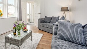 A modern living room with a grey striped sofa, a glass coffee table with flowers, and a lamp. - 2 bedroom accommodation in Foxhole, near St. Austell (Foxhole, near St. Austell)