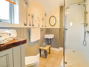 Un baño con inodoro, lavamanos, ducha y detalles decorativos en la pared.