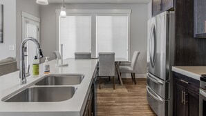A modern kitchen with stainless steel appliances, a double sink, and a dining area with a table and chairs. - New Modern Twin Home, Pet Friendly, Close to Airport, Downtown, Resorts and more (Millcreek)
