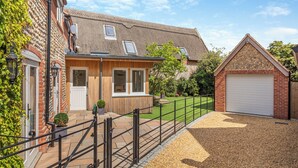 Il s’agit d’une propriété résidentielle avec une façade en briques, une extension en bois, un garage et une allée gravillonnée.