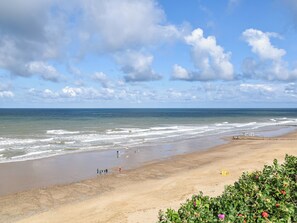 A beach with waves, a clear sky, and a few people. - 4 bedroom accommodation in Mundesley (Mundesley)